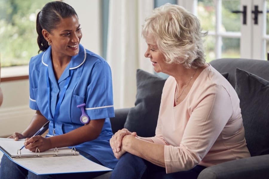 Real Client Experiences with Fresh Springs Care Services Smiling home care worker chatting with an elderly client on the sofa at home